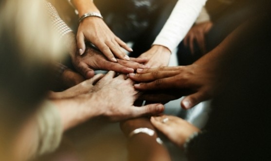 Team members putting hands together in a huddle.