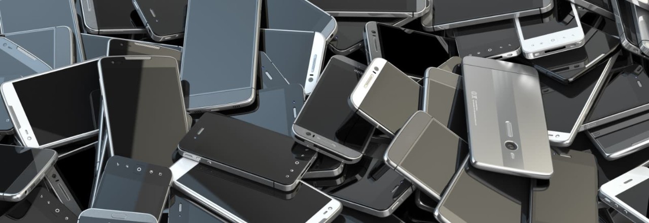 Old cellphones piled up in a bin.