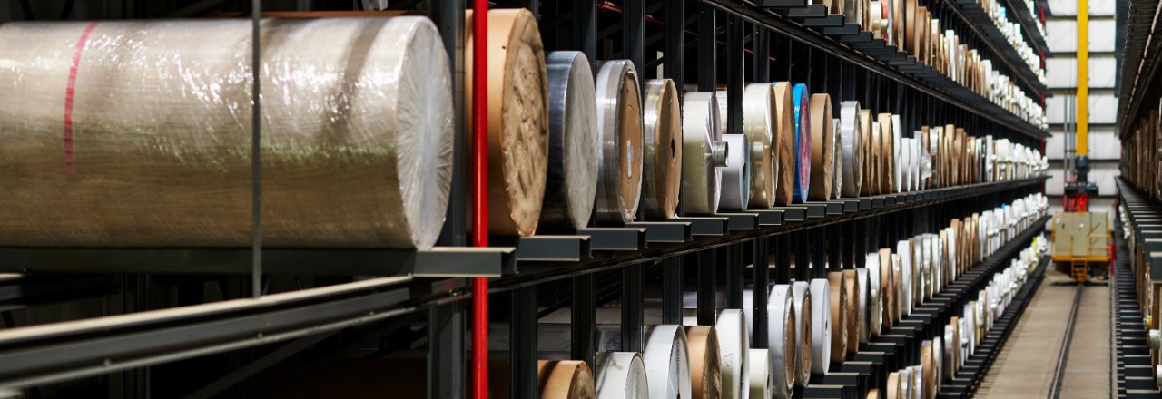 Material rolls on shelves in a warehouse.